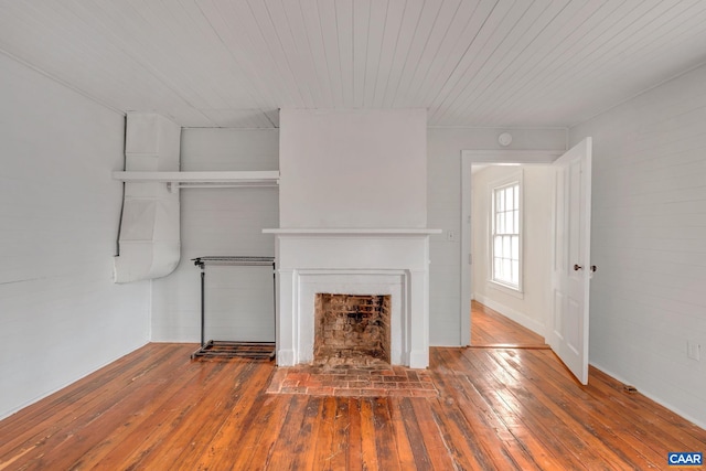 unfurnished living room with a fireplace with flush hearth, wood ceiling, and hardwood / wood-style floors