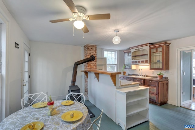 kitchen with open shelves, glass insert cabinets, wood finished floors, brown cabinetry, and a sink