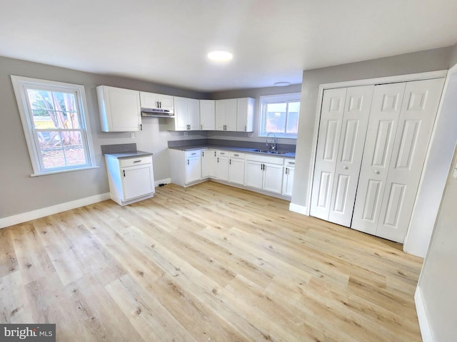 681 Fayette St, Cumberland, MD 21502 - kitchen with light wood-style flooring, a sink, under cabinet range hood, white cabinets, and baseboards