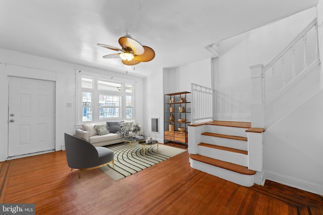 living area featuring baseboards, stairs, a ceiling fan, and wood finished floors