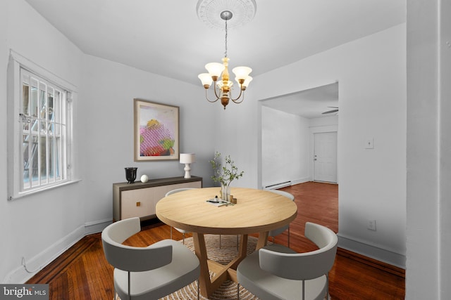 dining room with a baseboard heating unit, an inviting chandelier, wood finished floors, and baseboards