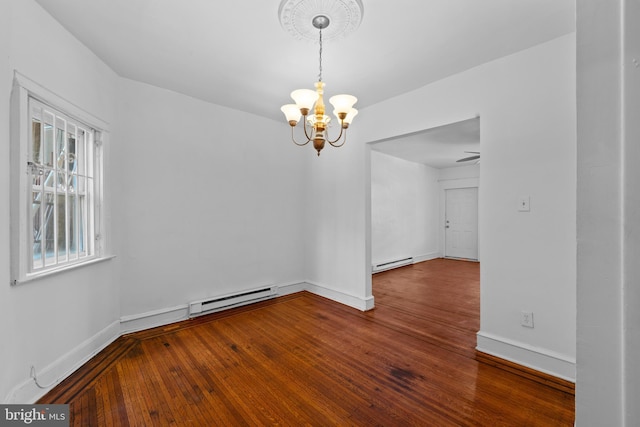 empty room with a chandelier, a baseboard heating unit, baseboards, and wood finished floors