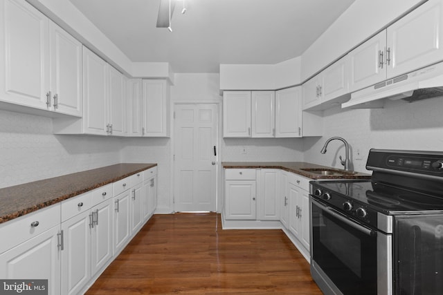 kitchen featuring under cabinet range hood, stainless steel range with electric stovetop, dark wood-style floors, white cabinetry, and a sink