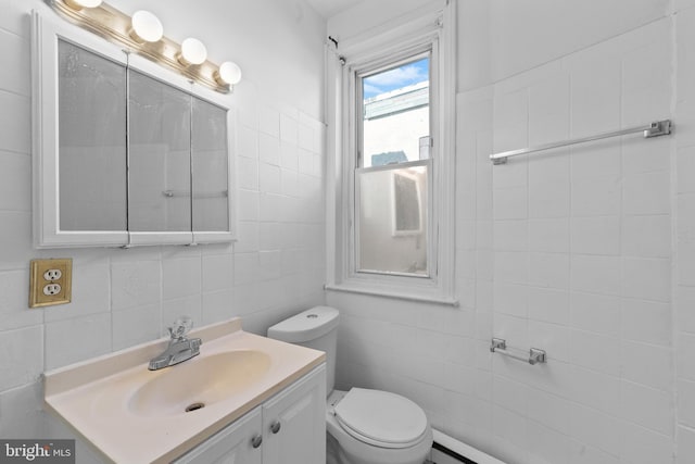 bathroom featuring baseboard heating, toilet, tile walls, and vanity