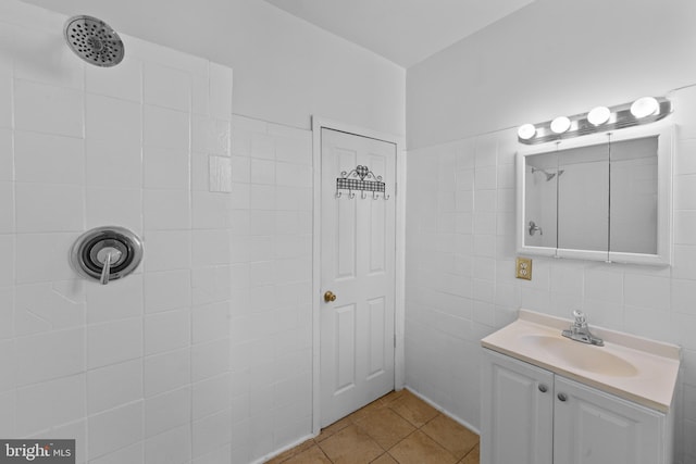 full bath with tiled shower, tile walls, vanity, and tile patterned flooring