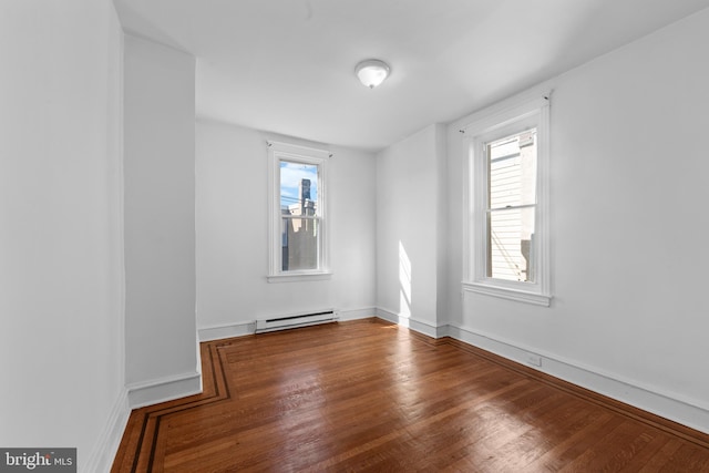 spare room with a baseboard heating unit and wood finished floors