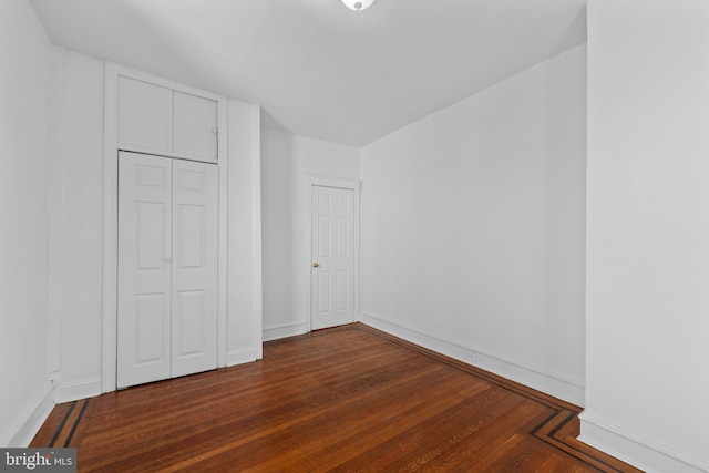 unfurnished bedroom featuring a closet, baseboards, and wood finished floors