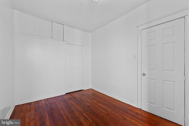 empty room with dark wood-style floors and baseboards