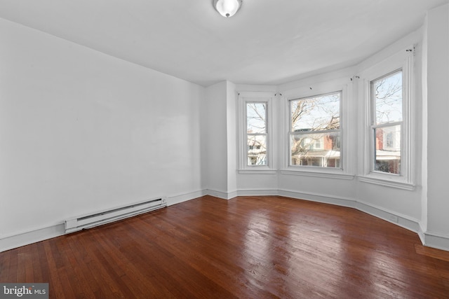 empty room featuring baseboard heating, baseboards, and wood finished floors