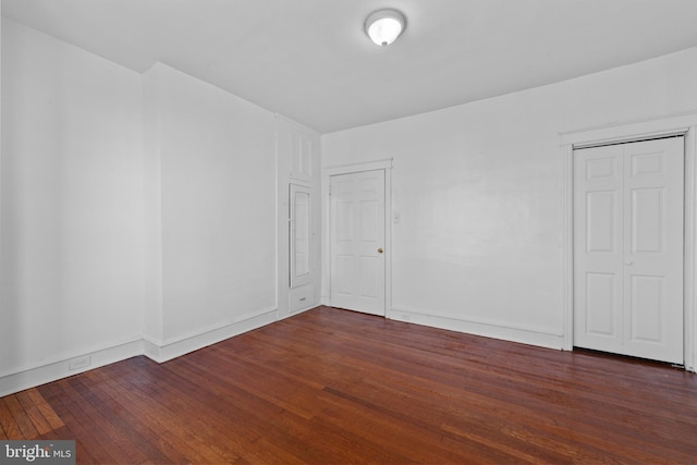 spare room featuring baseboards and dark wood-style flooring