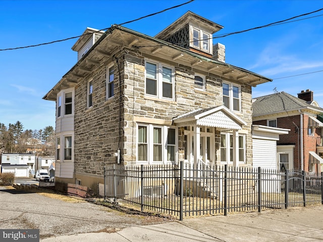 american foursquare style home with stone siding and a fenced front yard