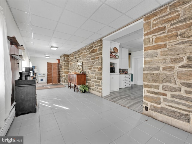 interior space with a paneled ceiling and light tile patterned flooring