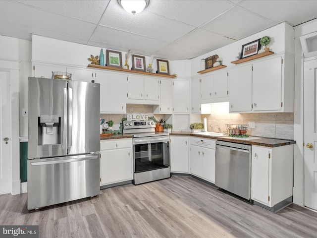 kitchen with decorative backsplash, appliances with stainless steel finishes, light wood-style floors, and a drop ceiling