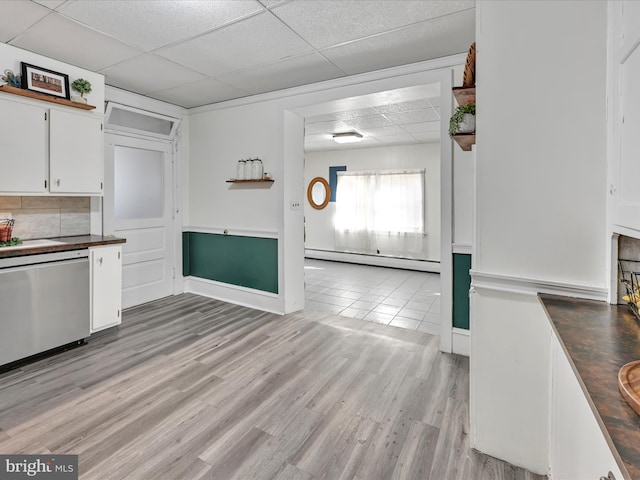 kitchen featuring white cabinets, light wood finished floors, a paneled ceiling, baseboard heating, and dishwasher