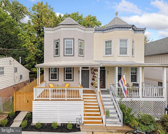 view of front of home featuring stairway, covered porch, stucco siding, and fence