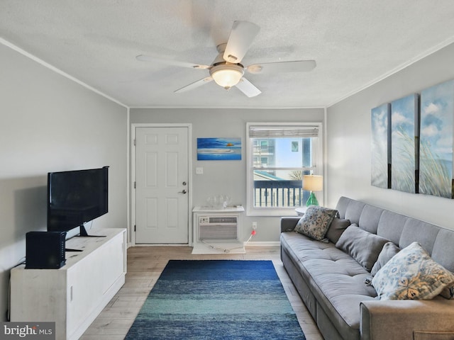 living room featuring ornamental molding, a wall mounted AC, a textured ceiling, light wood finished floors, and ceiling fan