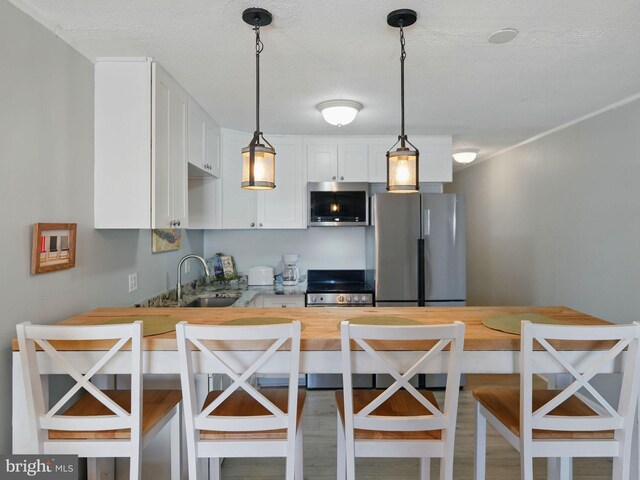 kitchen featuring a kitchen bar, butcher block counters, white cabinets, and stainless steel appliances