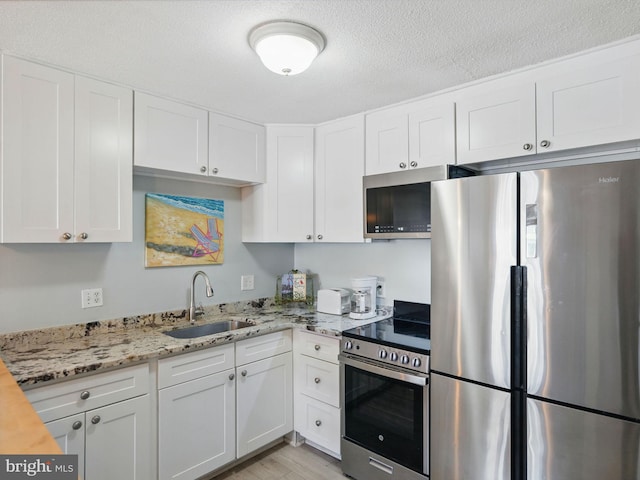 kitchen with white cabinetry, stainless steel appliances, and a sink