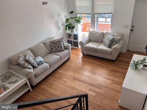 living area with visible vents and wood finished floors