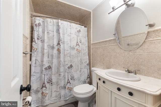 full bath with a wainscoted wall, toilet, a shower with shower curtain, tile walls, and vanity