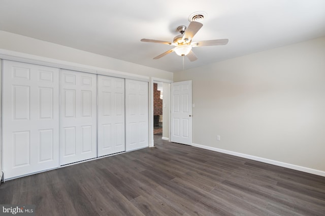 unfurnished bedroom featuring a closet, baseboards, and dark wood-style floors