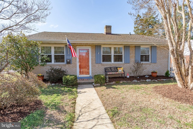 bungalow-style home with a front lawn, brick siding, a chimney, and a shingled roof