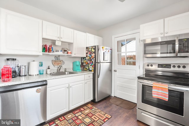 kitchen with dark wood finished floors, light countertops, white cabinets, stainless steel appliances, and a sink