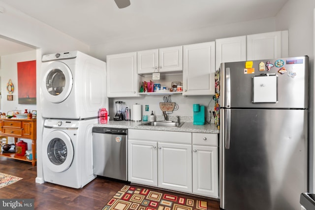 kitchen with a sink, stainless steel appliances, white cabinets, light countertops, and stacked washer / drying machine