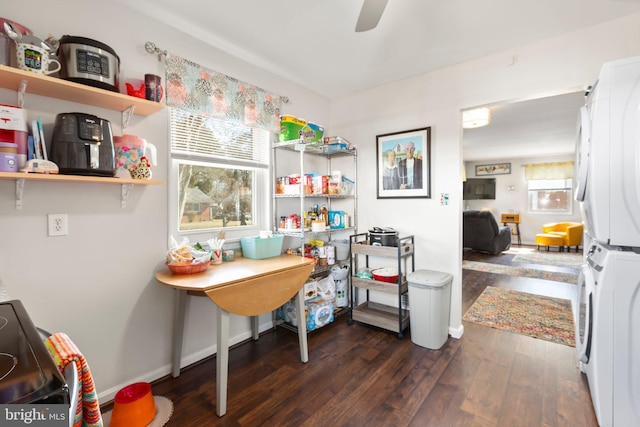 home office featuring ceiling fan, stacked washer and clothes dryer, baseboards, and wood finished floors