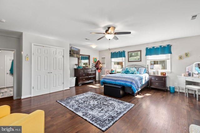 bedroom with a closet, visible vents, baseboards, and wood finished floors