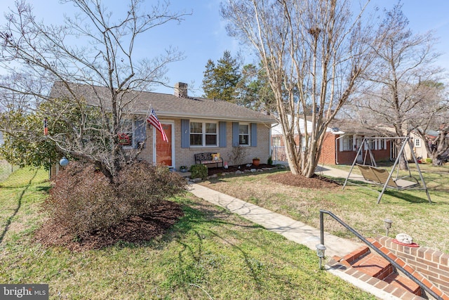 view of front of home with brick siding, a chimney, a playground, and a front yard