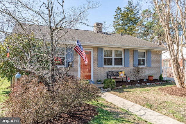 bungalow-style home featuring brick siding, a chimney, fence, and a shingled roof