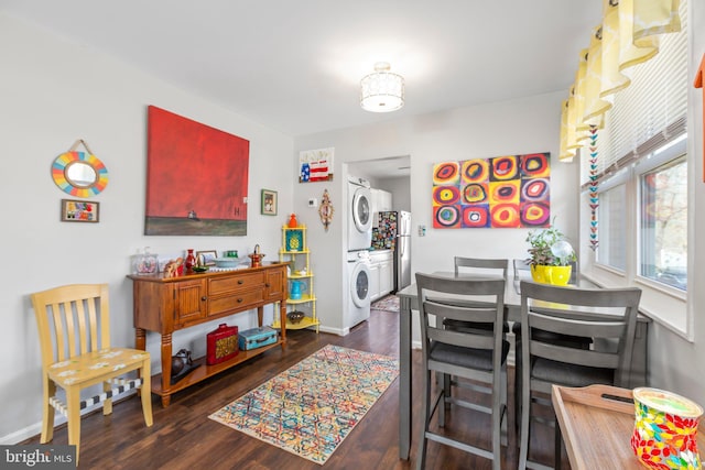 dining area featuring dark wood-style floors, stacked washer / dryer, and baseboards