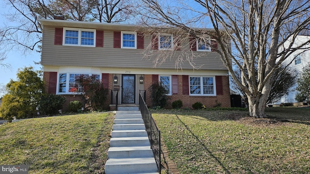 colonial home featuring brick siding, a chimney, and a front lawn