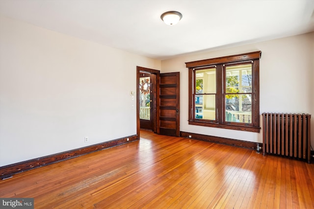 empty room featuring radiator, baseboards, and wood-type flooring