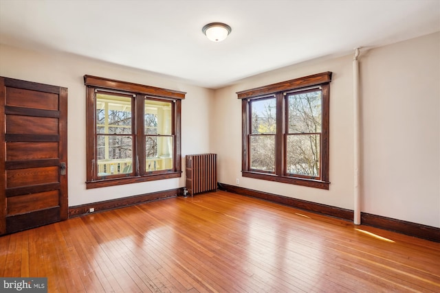 spare room with hardwood / wood-style floors, radiator heating unit, and baseboards