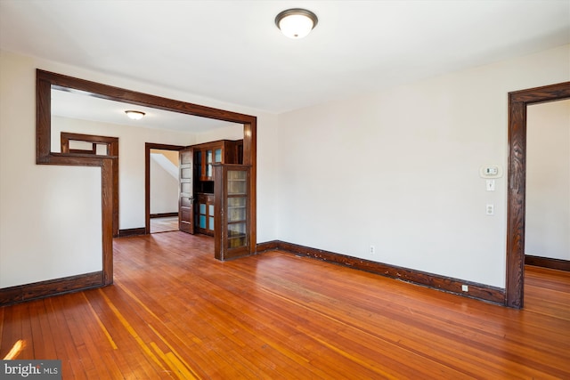 unfurnished room with french doors, baseboards, and wood-type flooring