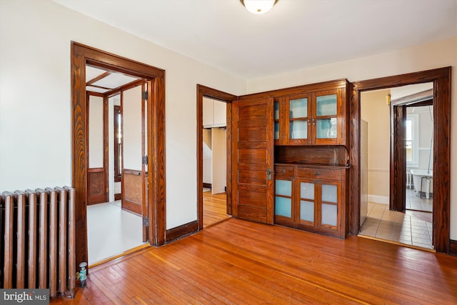 unfurnished room with hardwood / wood-style floors, radiator heating unit, and baseboards