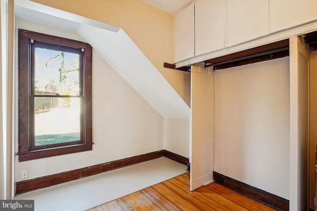 additional living space featuring lofted ceiling, plenty of natural light, baseboards, and wood-type flooring