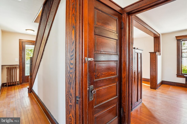 corridor with baseboards, radiator, and light wood-style flooring