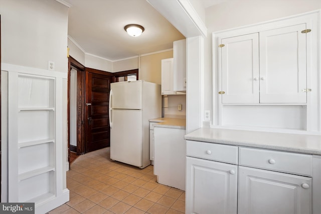 kitchen featuring ornamental molding, freestanding refrigerator, light tile patterned flooring, white cabinets, and light countertops