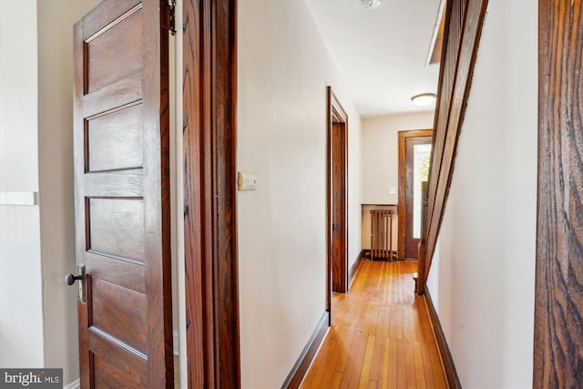 hallway featuring radiator, baseboards, and light wood finished floors