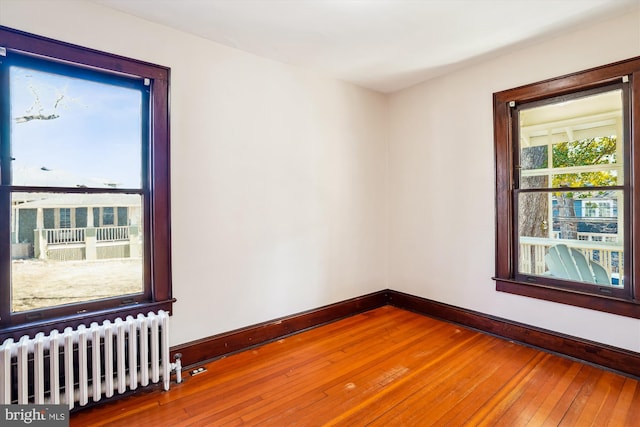 spare room featuring baseboards, wood-type flooring, and radiator heating unit