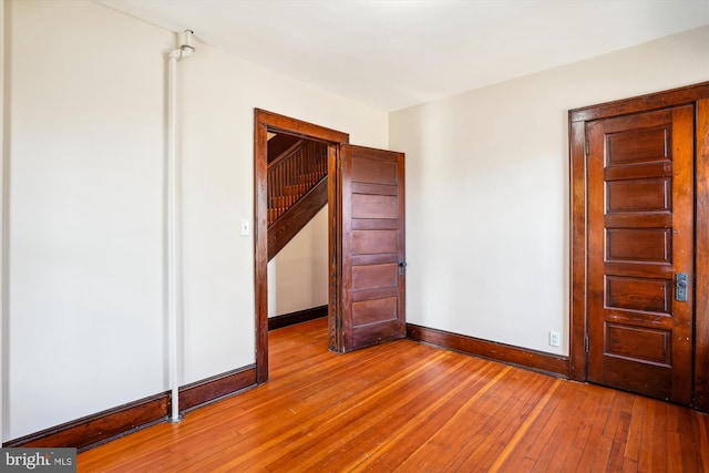 unfurnished bedroom with hardwood / wood-style flooring and baseboards