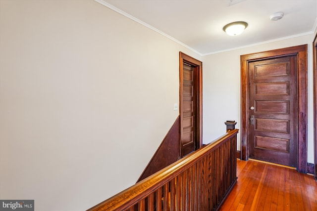 corridor featuring an upstairs landing, dark wood-type flooring, and ornamental molding