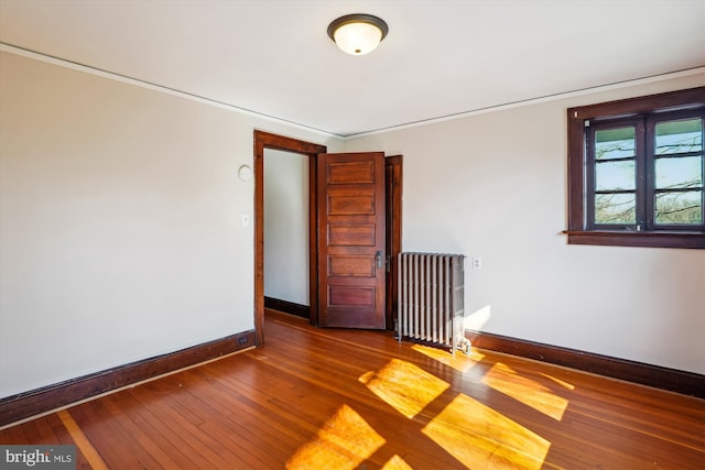 spare room with baseboards, radiator, and hardwood / wood-style floors