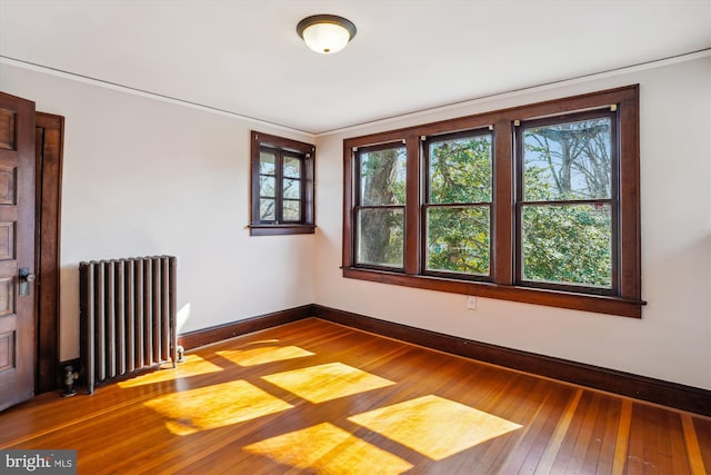 spare room featuring hardwood / wood-style flooring, radiator heating unit, and baseboards