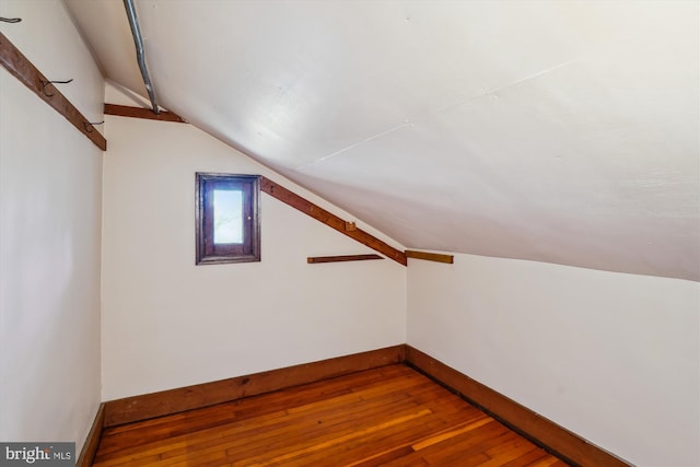 additional living space featuring hardwood / wood-style flooring, baseboards, and vaulted ceiling