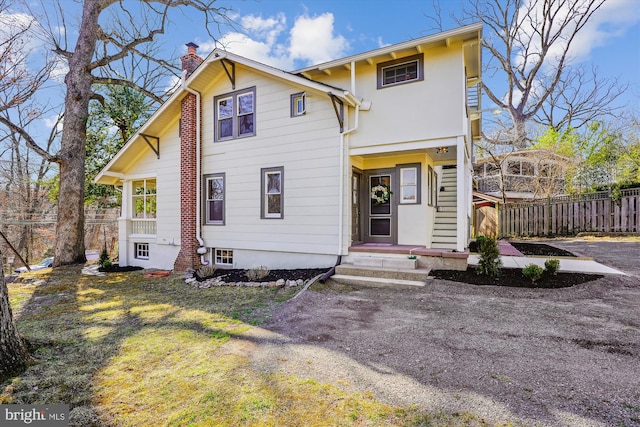 view of front of house featuring a chimney and fence