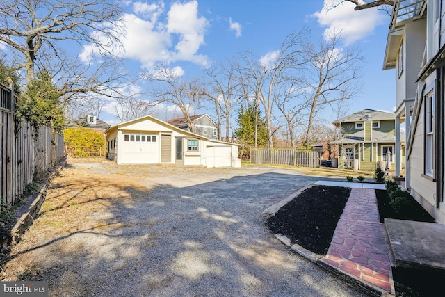 view of yard with a residential view, an outbuilding, driveway, and fence